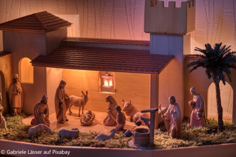 Holzkrippe mit beleuchtetem Stall, in dem Figuren der Weihnachtsgeschichte wie Maria, Josef, das Jesuskind, die Heiligen Drei Könige und verschiedene Tiere liebevoll arrangiert sind; warmes Licht erzeugt eine stimmungsvolle, weihnachtliche Atmosphäre.